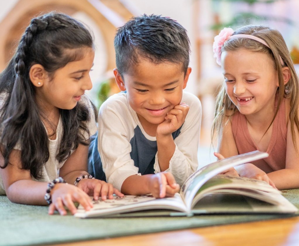 Three children reading and smiling